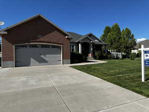 Ranch-style house featuring brick siding, a front yard, concrete driveway, and an attached garage