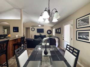 Dining area featuring an inviting chandelier, vaulted ceiling, baseboards, and arched walkways