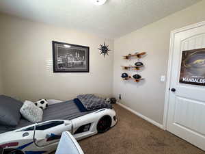 Carpeted bedroom with a textured ceiling and baseboards