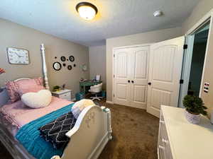 Bedroom with dark carpet, a closet, and a textured ceiling