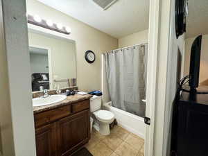 Full bathroom featuring tile patterned flooring, vanity, visible vents, and a textured ceiling