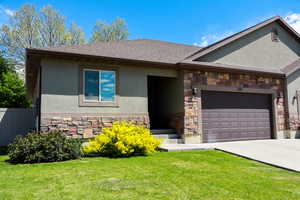 View of front of house featuring a front lawn, stone siding, stucco siding, and a garage