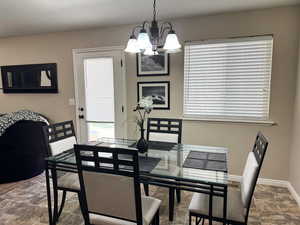 Dining room featuring an inviting chandelier, baseboards, and stone finish floor