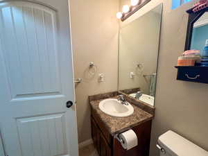 Half bathroom featuring vanity, toilet, and tile patterned floors