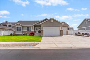 View of front facade featuring a garage, stucco siding, concrete driveway, and brick siding