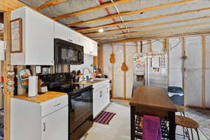 Kitchen with black appliances, a sink, white cabinetry, and light countertops
