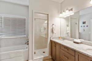 Full bath featuring a shower stall, a garden tub, and double vanity