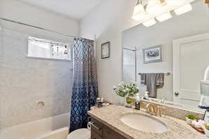 Bathroom with toilet, vanity, and shower / bathtub combination with curtain