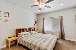 Carpeted bedroom featuring baseboards, ceiling fan, and recessed lighting