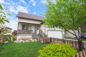View of front of property with an attached garage, stucco siding, stone siding, covered porch, and driveway