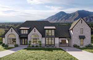 French provincial home featuring a mountain view, a front yard, and stone siding