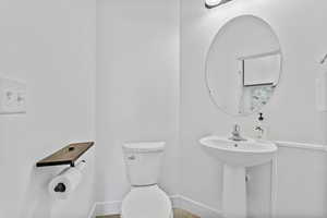 Half bath featuring toilet, baseboards, and a sink