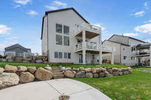 Rear view of property featuring a balcony, a yard, and a patio area