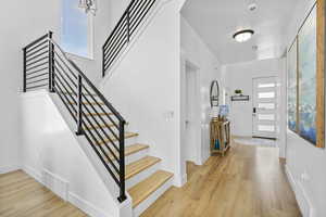 Entrance foyer featuring stairway, healthy amount of natural light, wood finished floors, and baseboards