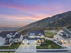 View of front facade with driveway, a mountain view, stone siding, board and batten siding, and an attached garage