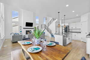 Dining space with recessed lighting, baseboards, light wood-style floors, a glass covered fireplace, and stairway
