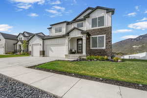 View of front facade featuring board and batten siding, stone siding, concrete driveway, and a mountain view