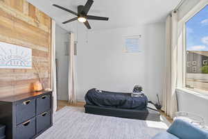 Bedroom featuring wood finished floors, wood walls, and a ceiling fan