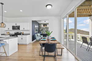 Kitchen featuring appliances with stainless steel finishes, white cabinets, light wood-type flooring, pendant lighting, and recessed lighting