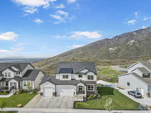 View of front facade featuring board and batten siding, stone siding, concrete driveway, a mountain view, and a residential view