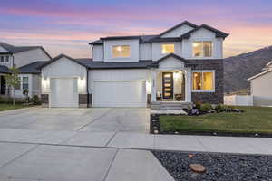 View of front facade featuring board and batten siding, stone siding, and concrete driveway