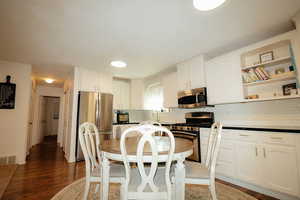 Kitchen featuring stainless steel appliances, backsplash, white cabinets, and wood finished floors