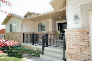 Entrance to property featuring brick siding and covered porch