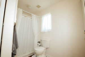 Primary Full bath with toilet, baseboards, and curtained shower