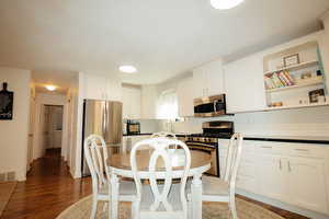 Kitchen featuring appliances with stainless steel finishes, tasteful backsplash, white cabinets, wood finished floors, and open shelves