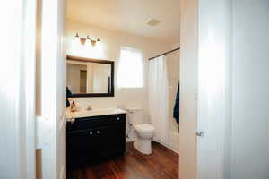 Bathroom featuring vanity, toilet, wood finished floors, and shower / tub combo