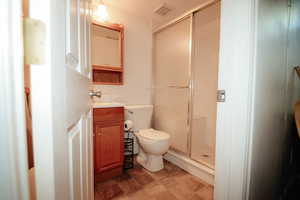 Bathroom featuring a stall shower, toilet, and vanity