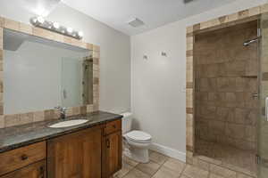 Full bathroom featuring a stall shower, toilet, tile patterned floors, vanity, and a textured ceiling