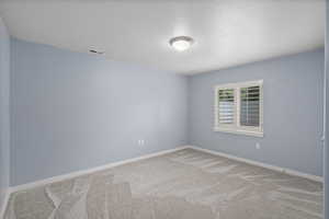 Carpeted spare room with a textured ceiling and baseboards