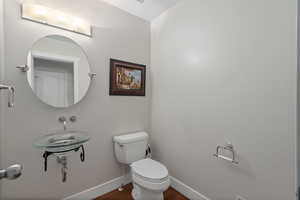 Bathroom featuring toilet, wood finished floors, and baseboards