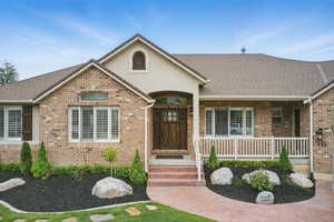 Single story home with brick siding, a porch, and stucco siding