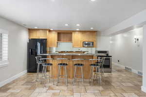 Kitchen featuring stainless steel appliances, baseboards, stone tile flooring, recessed lighting, and a textured ceiling
