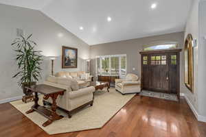 Living area with dark wood finished floors, recessed lighting, baseboards, and high vaulted ceiling