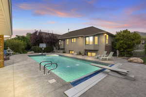 Pool at dusk featuring a patio and fence