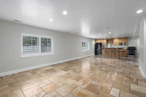 Living room featuring recessed lighting, stone tile floors, baseboards, and a textured ceiling