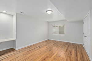 Unfurnished room featuring a textured ceiling, light wood-style floors, and baseboards
