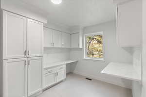 Mudroom featuring crown molding, built in study area, visible vents, and baseboards