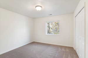 Unfurnished bedroom with carpet flooring, a closet, visible vents, and a textured ceiling