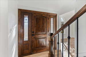 Foyer entrance featuring light wood finished floors and crown molding