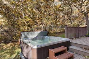 Deck featuring a hot tub and fence