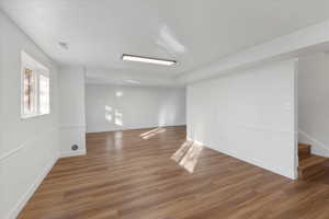 Spare room featuring wood finished floors, visible vents, baseboards, and stairs