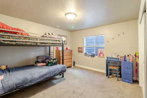Bedroom featuring a textured ceiling, carpet flooring, and baseboards