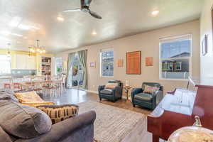 Living room with a ceiling fan, a chandelier, wood finished floors, recessed lighting, and baseboards
