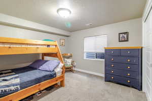 Bedroom featuring a textured ceiling, light carpet, and baseboards