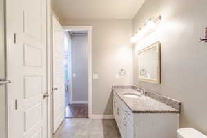 Half bathroom with vanity, tile patterned flooring, baseboards, and toilet