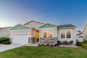 Craftsman-style house featuring concrete driveway, an attached garage, board and batten siding, and stone siding